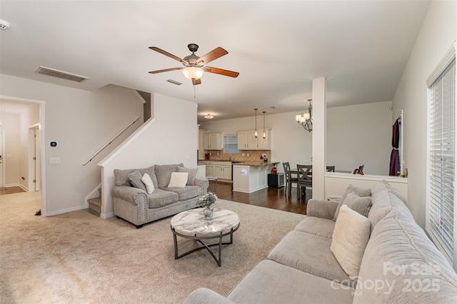 living room featuring light colored carpet and ceiling fan with notable chandelier