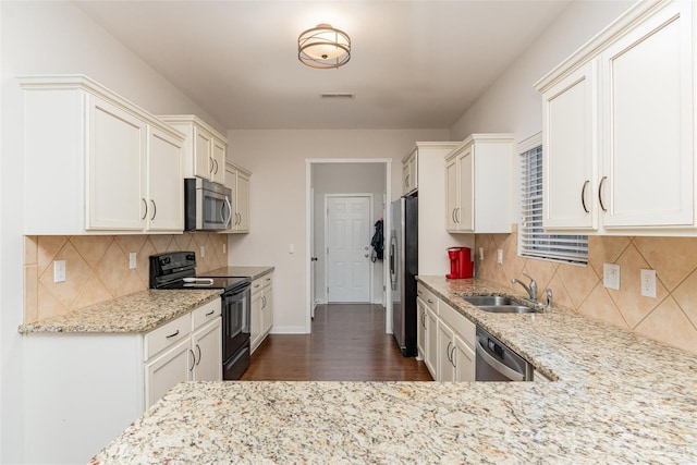 kitchen featuring stainless steel appliances, light stone countertops, sink, and decorative backsplash