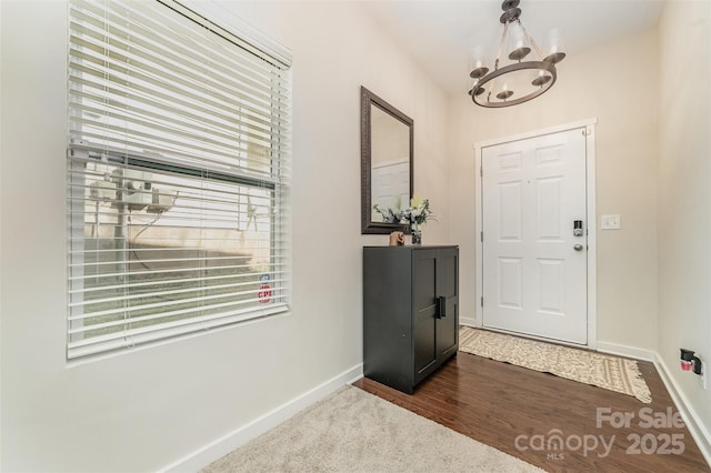 entryway featuring a chandelier, dark wood-type flooring, and baseboards