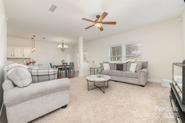 living room with light carpet, ceiling fan with notable chandelier, visible vents, and baseboards