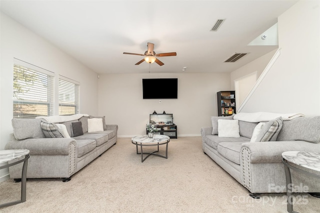 living room featuring baseboards, a ceiling fan, visible vents, and light colored carpet