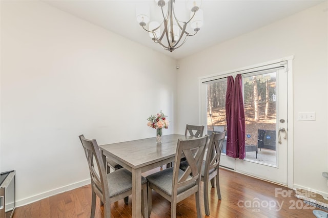 dining room with dark wood-type flooring, a notable chandelier, and baseboards