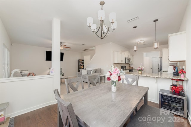 dining space with baseboards, visible vents, dark wood-type flooring, and ceiling fan with notable chandelier