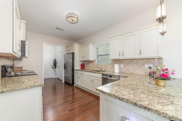 kitchen featuring decorative light fixtures, dark wood finished floors, appliances with stainless steel finishes, white cabinetry, and a sink