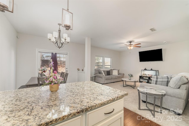 kitchen with visible vents, open floor plan, decorative light fixtures, light stone countertops, and cream cabinets