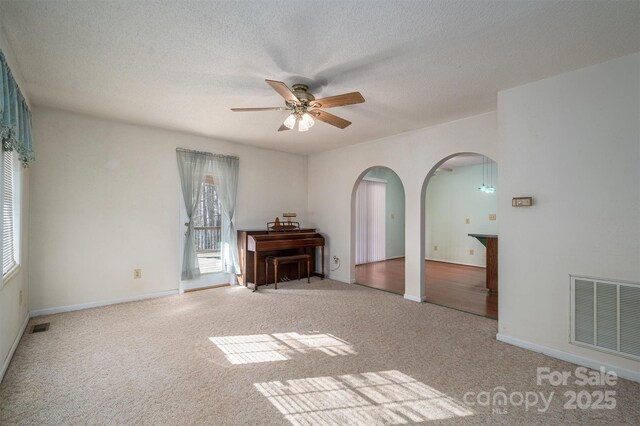 unfurnished living room featuring ceiling fan, light carpet, and a textured ceiling