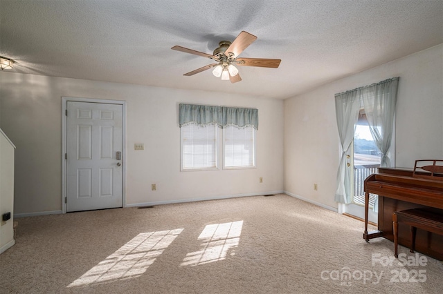 interior space with ceiling fan, plenty of natural light, light colored carpet, and a textured ceiling