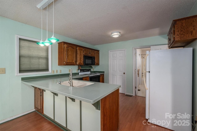 kitchen with sink, hanging light fixtures, kitchen peninsula, white fridge, and electric stove