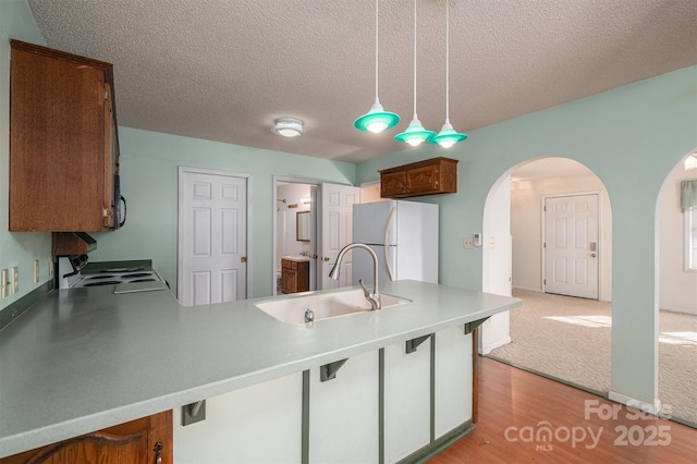 kitchen featuring pendant lighting, sink, white refrigerator, electric range, and kitchen peninsula