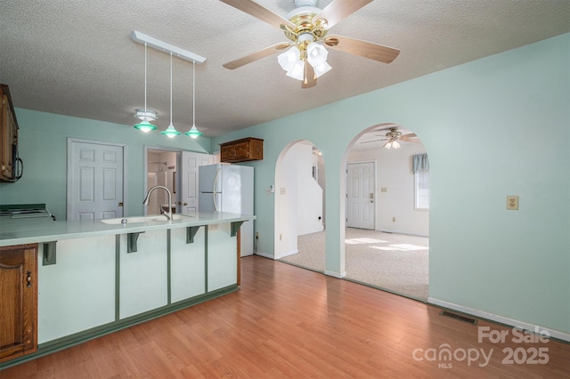 kitchen featuring light hardwood / wood-style flooring, sink, white fridge, and a textured ceiling