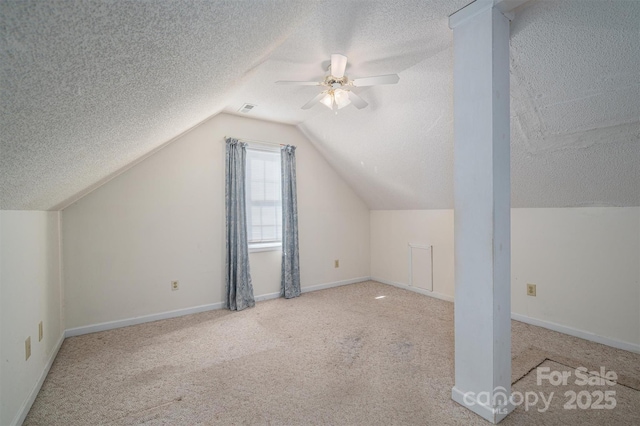 additional living space featuring vaulted ceiling, light carpet, and a textured ceiling