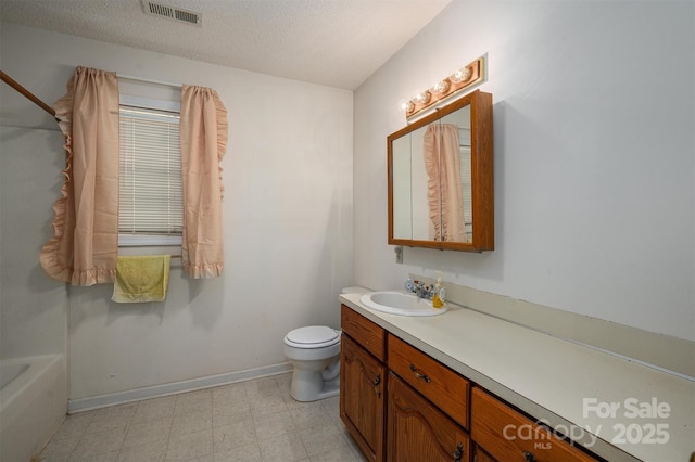 bathroom featuring vanity, a tub to relax in, a textured ceiling, and toilet