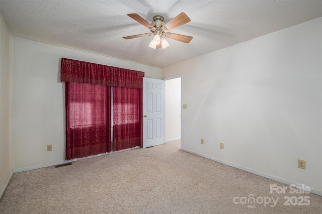 unfurnished room with ceiling fan, light colored carpet, and a textured ceiling