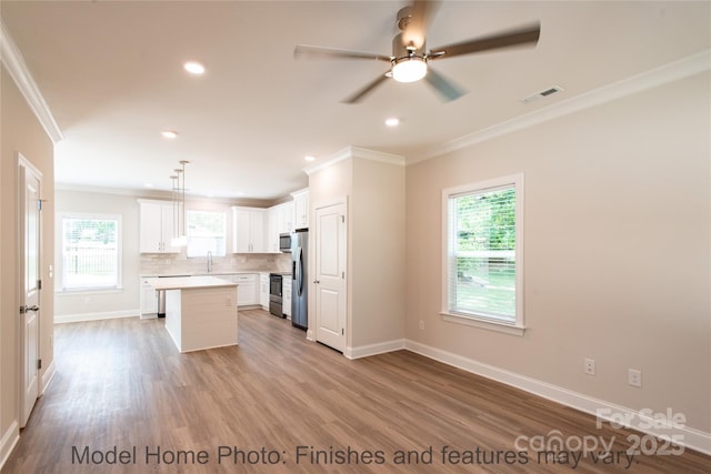 kitchen with a kitchen island, decorative light fixtures, tasteful backsplash, white cabinetry, and stainless steel appliances