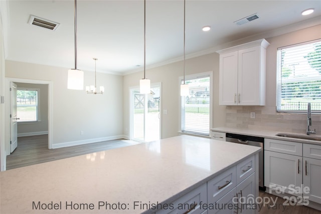 kitchen with sink, hanging light fixtures, ornamental molding, white cabinets, and stainless steel dishwasher