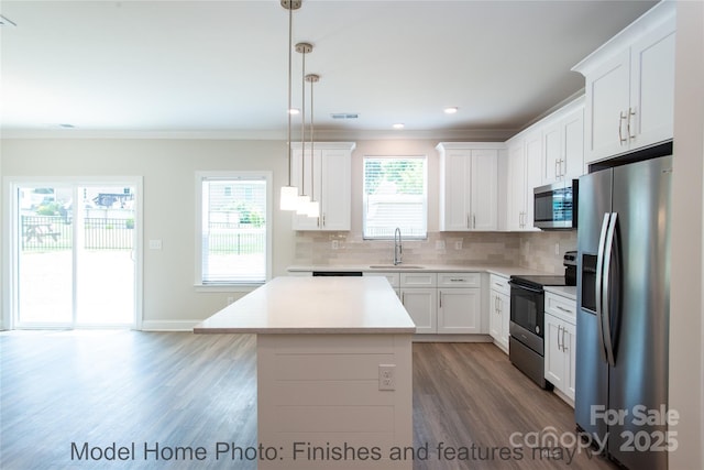 kitchen featuring decorative light fixtures, a center island, white cabinets, and appliances with stainless steel finishes