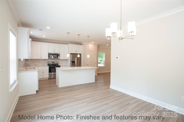 kitchen with stainless steel appliances, a kitchen island, hanging light fixtures, and white cabinetry