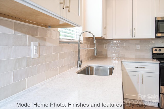 kitchen featuring white cabinetry, sink, decorative backsplash, and stainless steel appliances