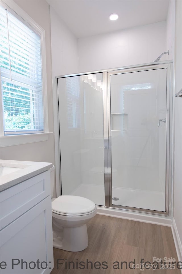 bathroom with vanity, hardwood / wood-style flooring, a shower with shower door, and toilet