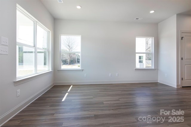 empty room featuring a wealth of natural light, dark wood-style flooring, visible vents, and recessed lighting