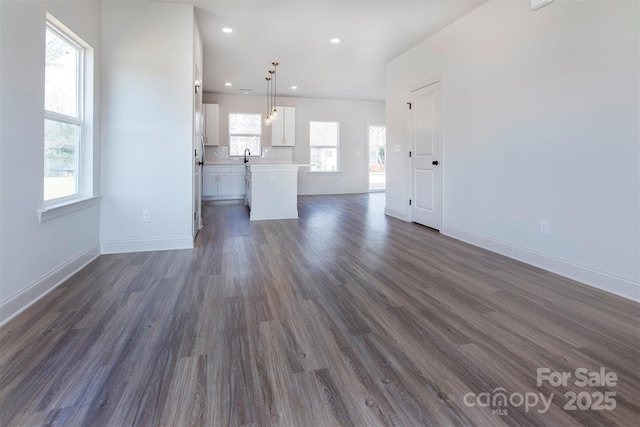 unfurnished living room with recessed lighting, dark wood-style flooring, a sink, and baseboards