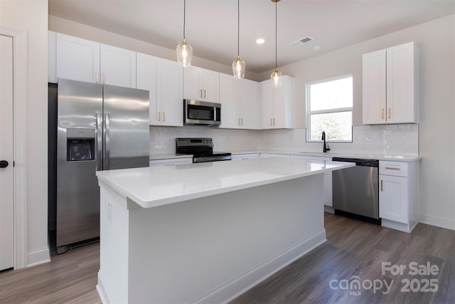 kitchen with stainless steel appliances, a kitchen island, and white cabinets