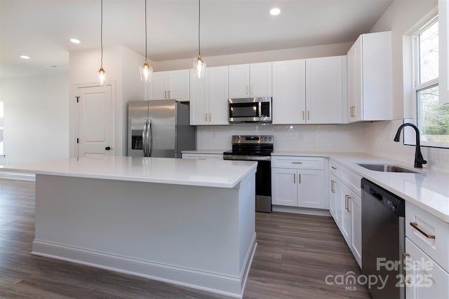 kitchen featuring a center island, stainless steel appliances, hanging light fixtures, white cabinets, and a sink