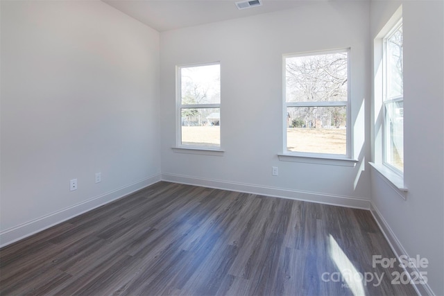 spare room with visible vents, dark wood finished floors, and baseboards