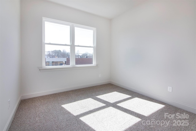 empty room featuring carpet and baseboards