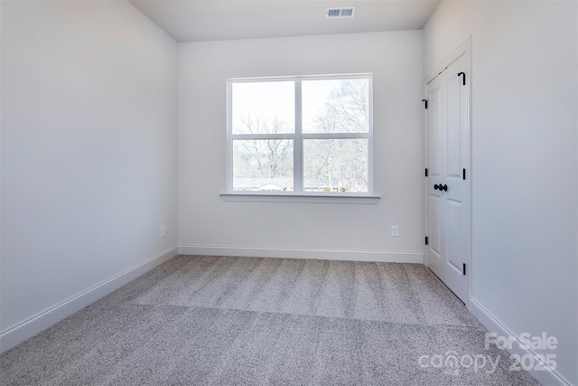 carpeted spare room featuring visible vents and baseboards