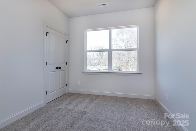 spare room featuring baseboards, visible vents, and light colored carpet