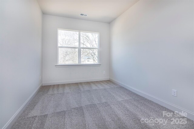 empty room featuring carpet, visible vents, and baseboards