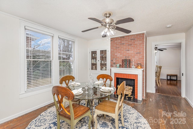 dining room featuring ceiling fan, a fireplace, dark hardwood / wood-style flooring, and a textured ceiling