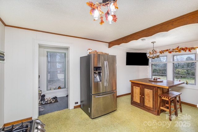 kitchen featuring stainless steel fridge, an inviting chandelier, hanging light fixtures, ornamental molding, and a textured ceiling