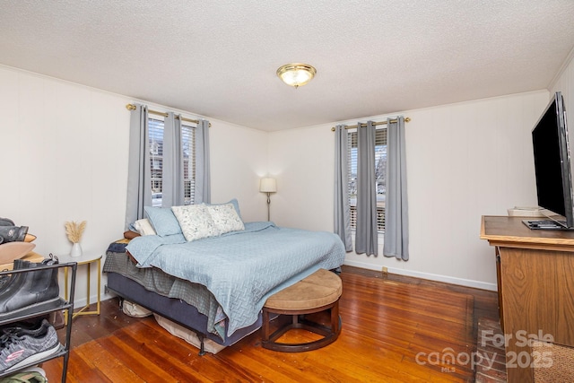 bedroom featuring multiple windows, dark wood-type flooring, and a textured ceiling