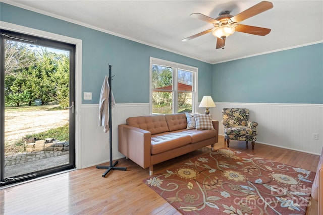 living area featuring ornamental molding, ceiling fan, and light wood-type flooring