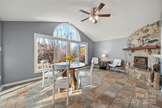 dining room with vaulted ceiling, a stone fireplace, and ceiling fan