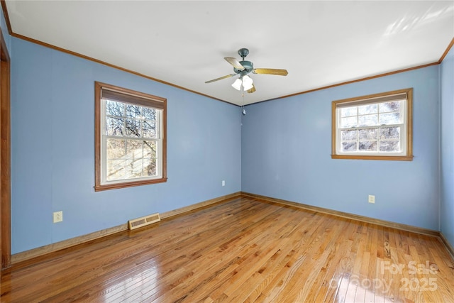 spare room featuring ornamental molding, a healthy amount of sunlight, and light hardwood / wood-style floors