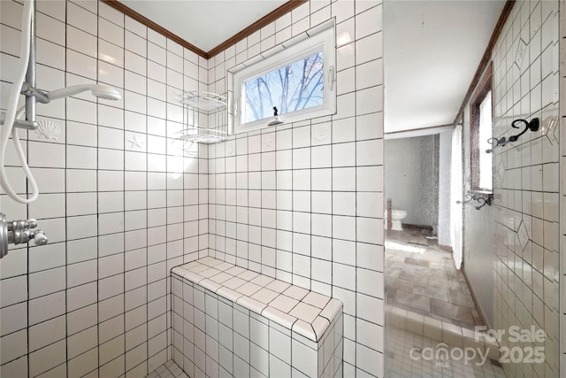 bathroom with ornamental molding and tiled shower