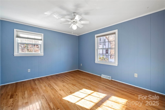 empty room with ceiling fan, plenty of natural light, ornamental molding, and light hardwood / wood-style floors