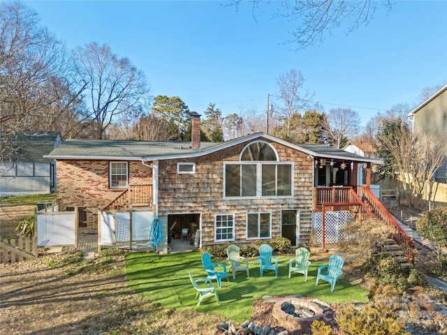 rear view of property with a yard and an outdoor fire pit