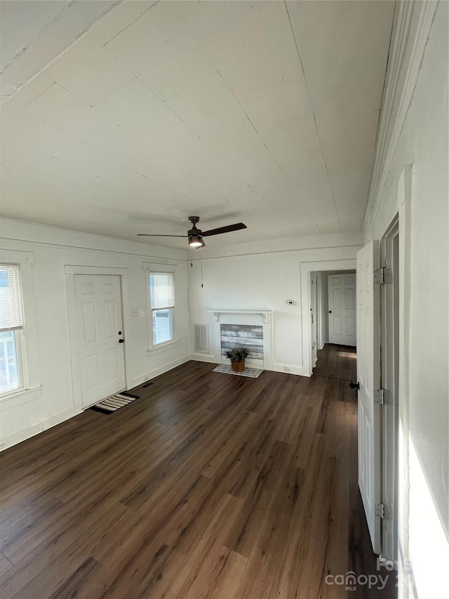 unfurnished living room featuring dark wood-type flooring and ceiling fan