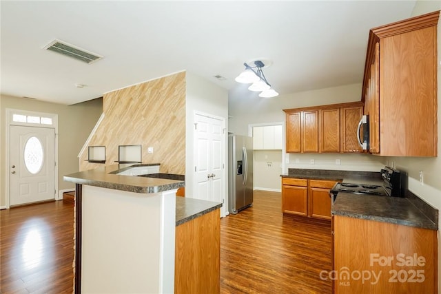 kitchen with a kitchen island, appliances with stainless steel finishes, and dark wood-type flooring