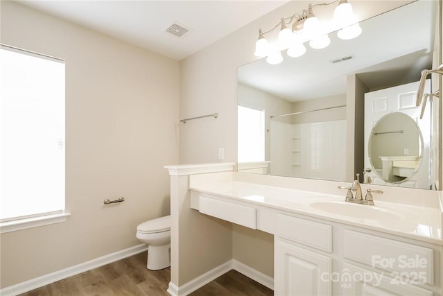 bathroom featuring vanity, hardwood / wood-style floors, a shower, and toilet