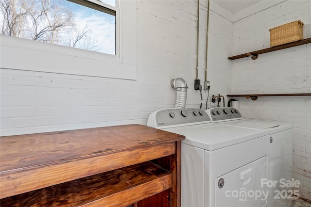 laundry room with brick wall and washing machine and clothes dryer