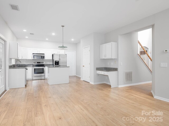 172 Foxtail Dr, Mooresville, NC 28117 - kitchen featuring stainless steel appliances, a sink, dark countertops, light wood-type flooring, and white cabinetry