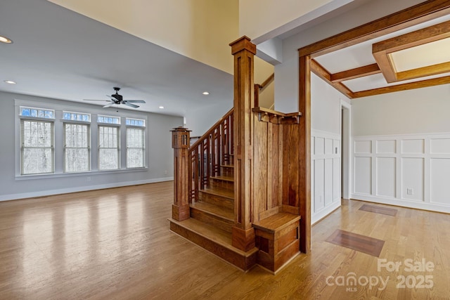 stairs with decorative columns, wood-type flooring, and ceiling fan