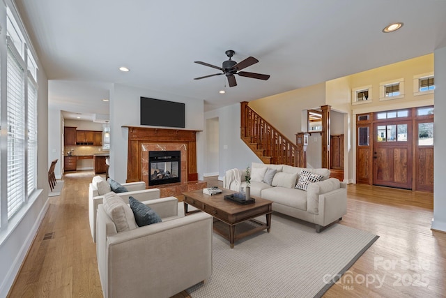 living room with a fireplace, light hardwood / wood-style floors, and ceiling fan