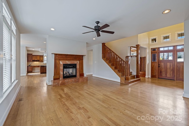 unfurnished living room featuring a fireplace, light hardwood / wood-style flooring, and ceiling fan