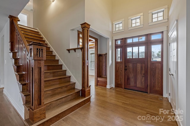 entryway with a high ceiling, decorative columns, and light hardwood / wood-style floors